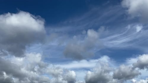 Weiße und graue Wolken fliegen am blauen Himmel mit Sonnenstrahlen. Timelapse-Bewegungshintergrundaufnahme