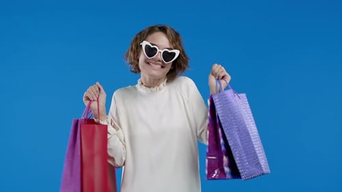 Woman Smiling and Holding Shopping Bags in Studio