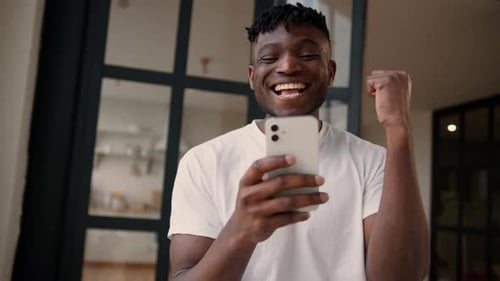Excited Young Adult Man Celebrating Using Smartphone