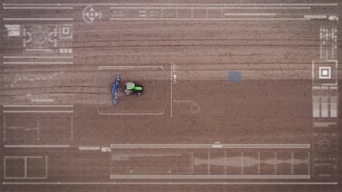 Aerial view of a drone that monitors, with futuristic holographic graphics, a tractor that works t
