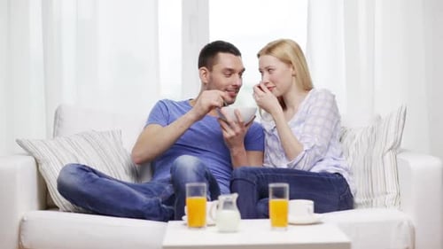 Couple Eating Breakfast Together on the Sofa at Home