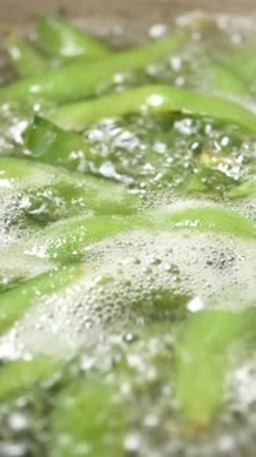 Green Beans are Being Cooked in Water on a Stove with Bubbles
