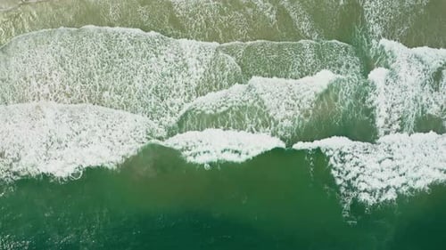 Aerial views of beautiful beach with tropical waves rolling into the shore.