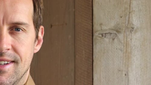 Man's Smiling Face Close Up Against Wooden Wall