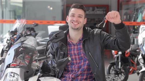 Enthusiastic Man Shaking Motorcycle Keys with a Smile