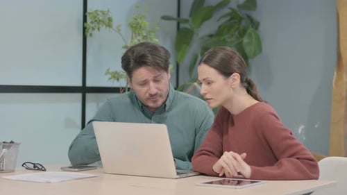 Man and Woman Discussing Laptop in Office