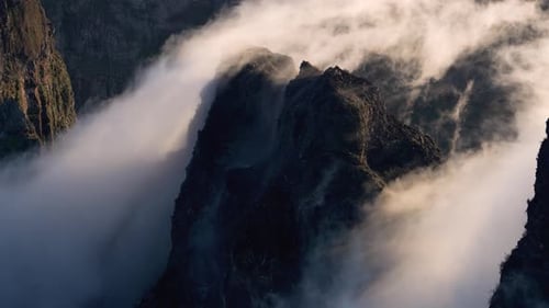 Majestic clouds dance over rugged mountain peaks in serene landscape