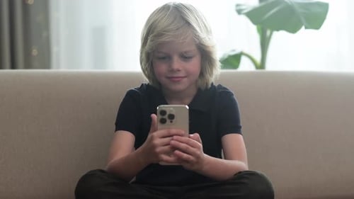 Boy Enjoying Mobile Phone on Couch at Home
