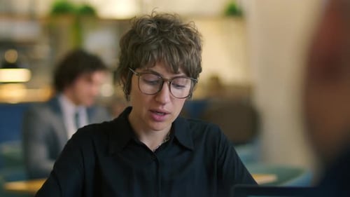 Young Woman Speaking with Business Partner during Meeting at Cafe