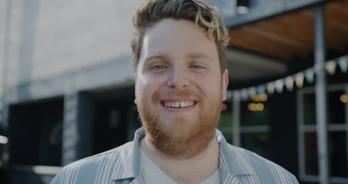 Carefree Young Man Smiling and Laughing Looking at Camera Outdoors in Modern City