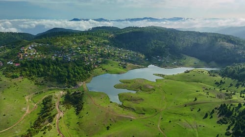 Aerial View of Lush Green Landscape with Serene Lake and Rolling Hills