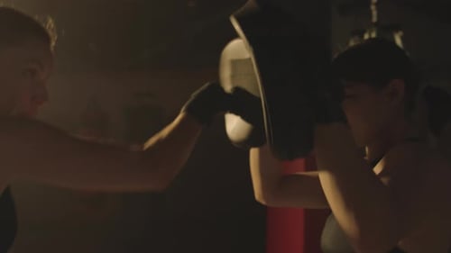 Woman Boxer Training with Pads in Gym