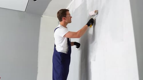 Young Adult Painting Wall Gray with Paint Roller
