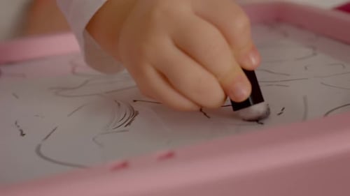 Toddler Hand Erasing Drawing on Pink Tablet