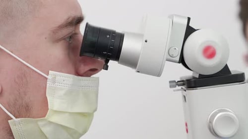 Man Looking Through Microscope Wearing Mask