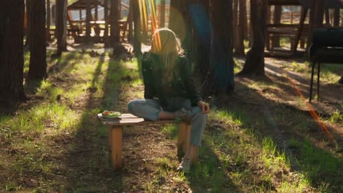 Young Woman Eating Lunch in Forest Sunlight