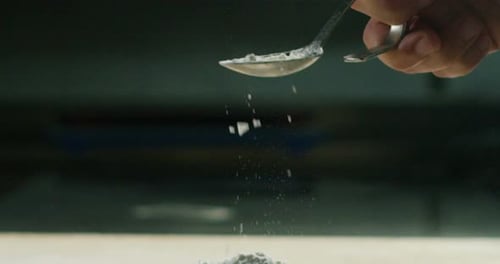 White Powder Poured from Spoon onto Pile