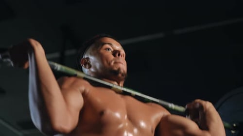 Closeup Shooting From Bottom to Top Overhead Barbell Press Performed By a Young Mixed Race Athlete