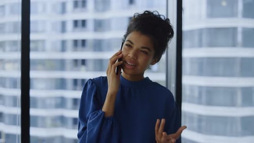 Happy african american businesswoman talking smartphone in modern office