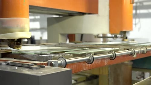 Drilling a hole into glass panel on a modern orange machine with a moving table. Glassworking indust