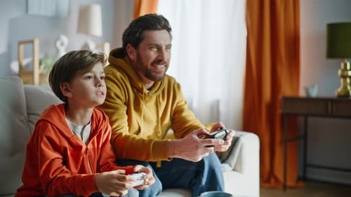 Father and Son Play Video Games Together at Home