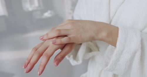 Woman Applying Lotion to her Hands in Robe