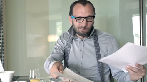 Man Eating Breakfast While Reviewing Documents