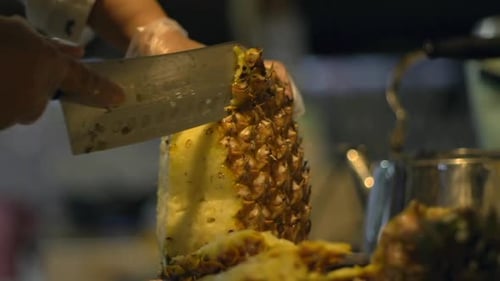 Husk being removed from pineapple with kitchen knife, filmed in slow motion as close up shot