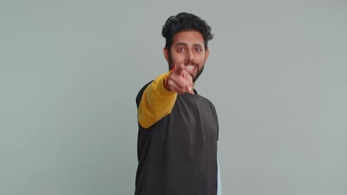 Indischer Mann lächelt aufgeregt und zeigt in die Kamera und wählt einen glücklichen Gewinner aus und sagt Hallo du