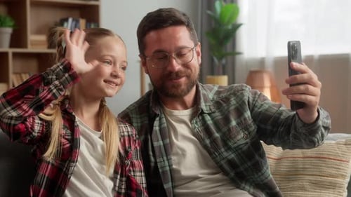 Cheerful Father and Child Waving During Video Call