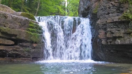 Waterfall on Mountain River with White Foamy Water Falling Down From Rocky Formation in Summer
