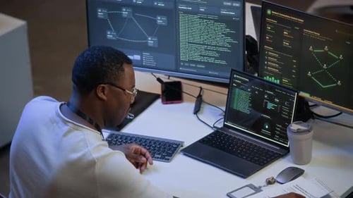 Network Administrator Reviewing Data and Codes on Computers in Office