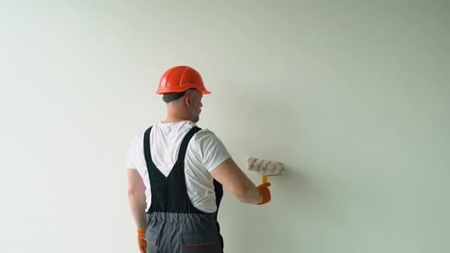 Man Painting a White Wall with a Paint Roller