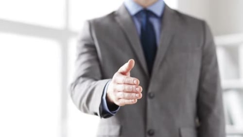 Empresário estende a mão para aperto de mão dando boas-vindas à nova parceria no escritório