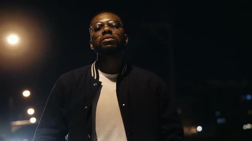 Panning View Of A Man In Jacket Under The Streelights While The Camera Slowly Zooms Out