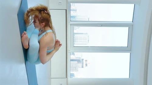 Vertical Screen: woman practicing Psychic Union Pose or Mudrasana with namaste