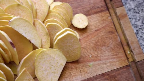 Fresh Sliced Raw Sweet Potatoes Prepared on a Wooden Cutting Board