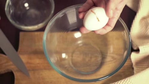 Egg cracking into glass bowl for baking preparation