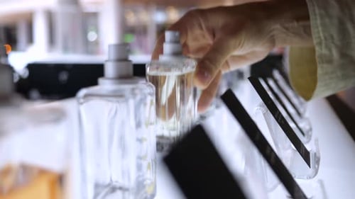 Close Up of Perfume in Showcase Hand of Woman Buyer Takes Perfume Bottle to Inhale Fragrance Before
