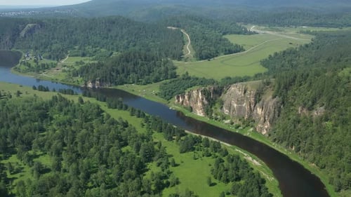 Revealing Shot of a River Flowing Among Green Forest and Mountains