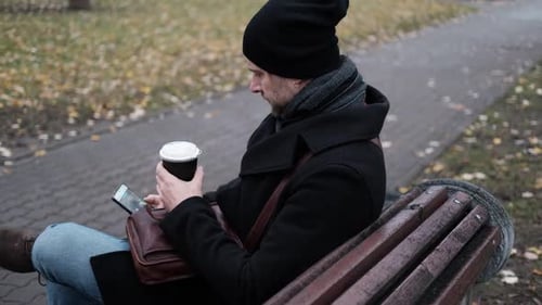 Pensive Hipster Drinking Coffee in the Urban Street Handsome Man Wearing Black Hat and Coat Walking