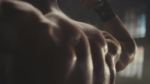 Muscular Person Flexing Back and Arms in Gym