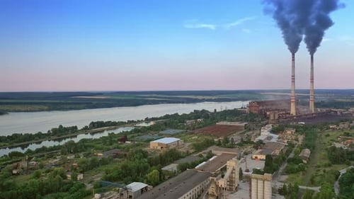 Industrial factory in the cityscape near the river in the evening.
