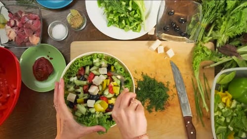 Top shot of preparing fresh Greek salad from feta cheese, tomatoes, cucumbers, olives, lettuce