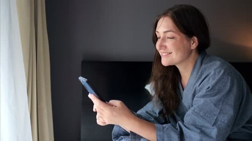 Woman Using Smartphone on Hotel Bed