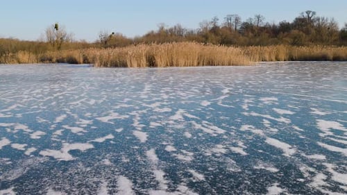 A frozen lake stretches across the frame, its surface covered in delicate white frost patterns.