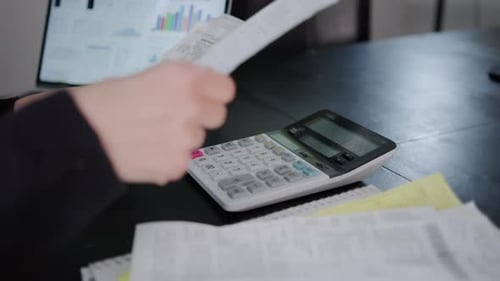 Woman Checking Bills Taxes Bank Account Balance and Calculating Expenses in the Living Room at Home