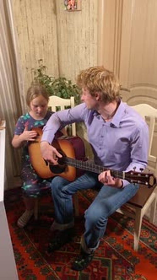 Guitar Lesson: Father Teaching Daughter at Home
