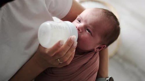 Adorable Infant Feeding From Bottle in Parent's Arms