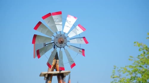 A Vintage Windmill Spins with the Wind on a Blue Sky Rural Scene